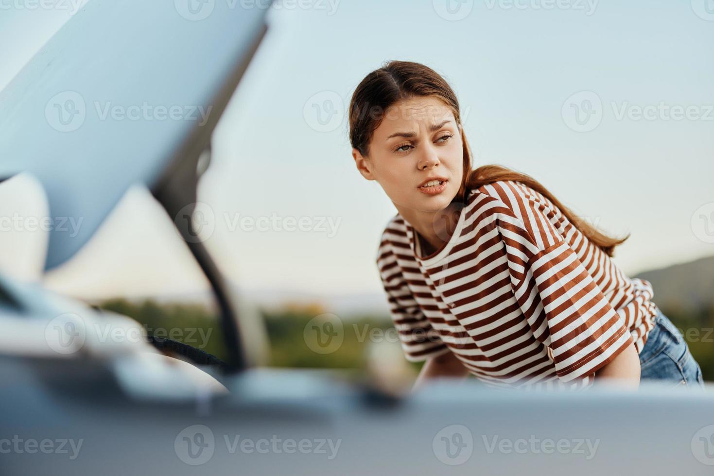 en ledsen kvinna utseende i misstro på henne bruten ner bil på de väg medan reser och gör inte känna till Vad till do foto