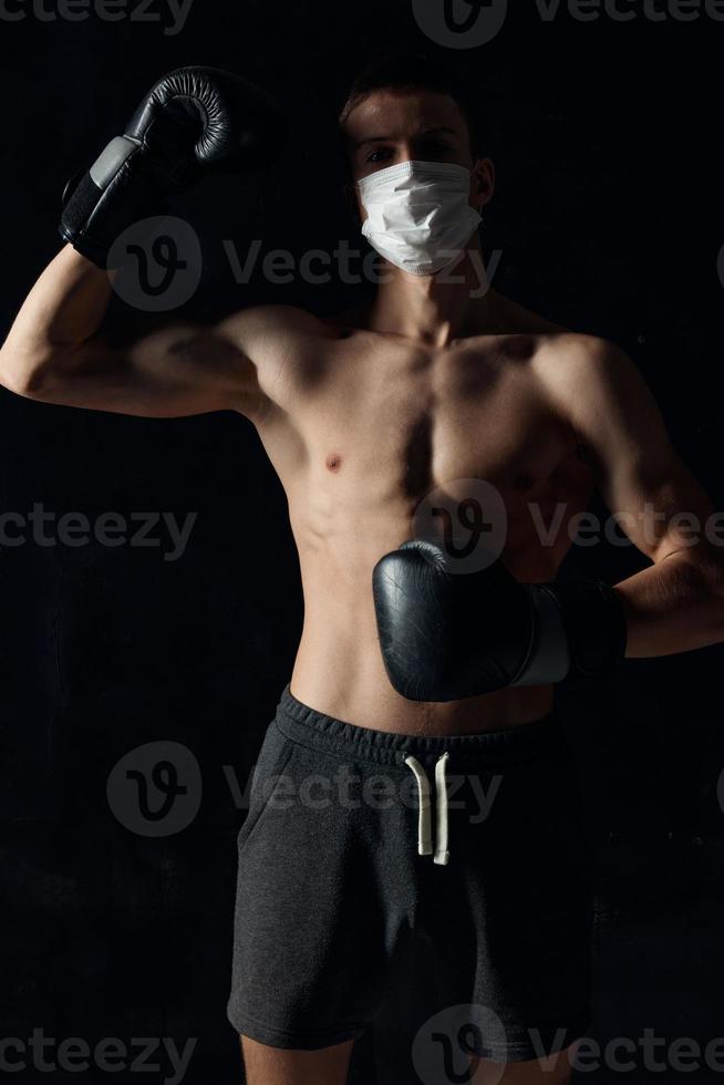 boxare i en medicinsk mask på en svart bakgrund handskar idrottare naken torso modell kroppsbyggare foto