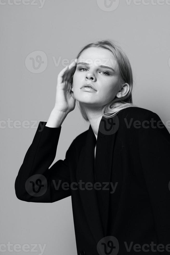 mode modell flicka Framställ med henne händer upp i de studio i svart och vit stil i en klassisk jacka foto