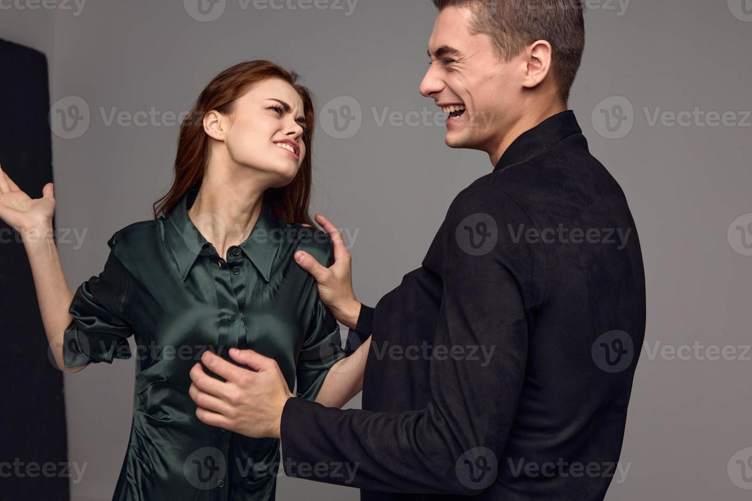 glad man och aggressiv kvinna slag i de ansikte konflikt grå backgroun foto