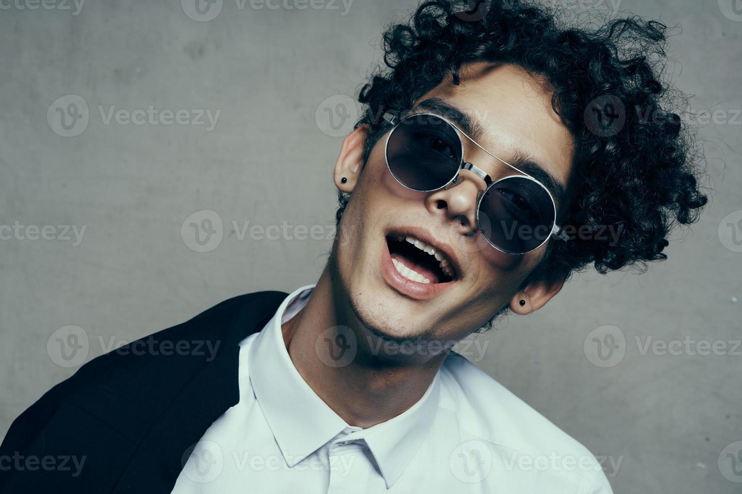 porträtt av en Lycklig lockigt hår kille i en klassisk kostym och glasögon foto