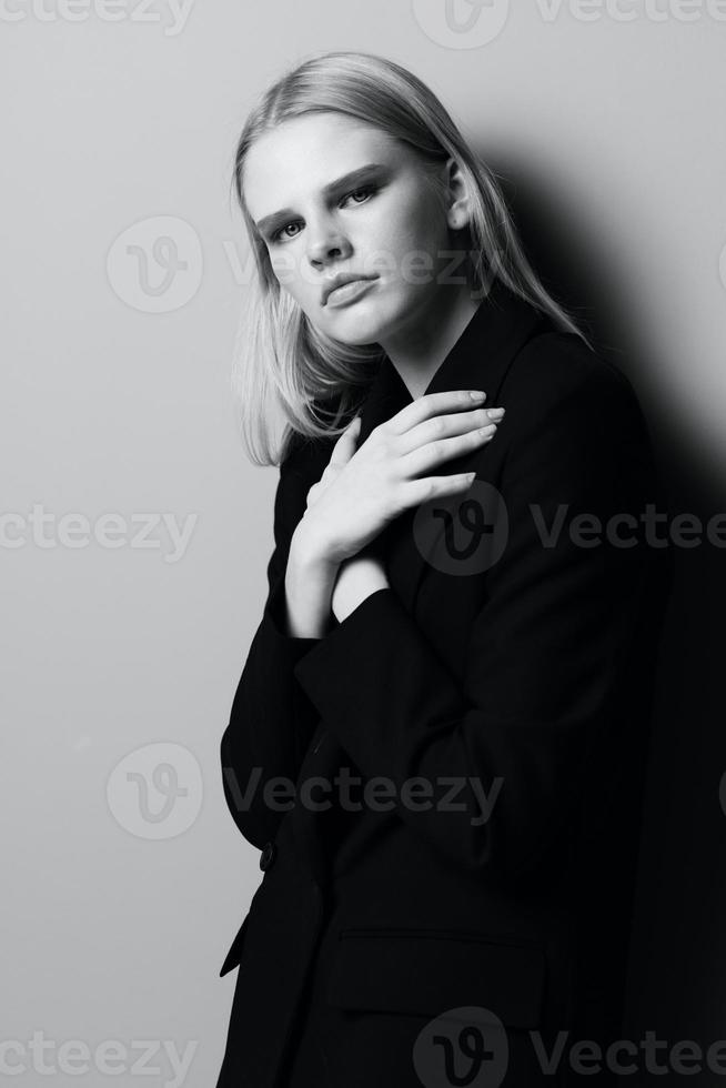 en eleganta professionell modell går över henne vapen på henne bröst och innehar en jacka medan Framställ i de studio. modern eleganta Foto. begrepp för Kläder märken foto