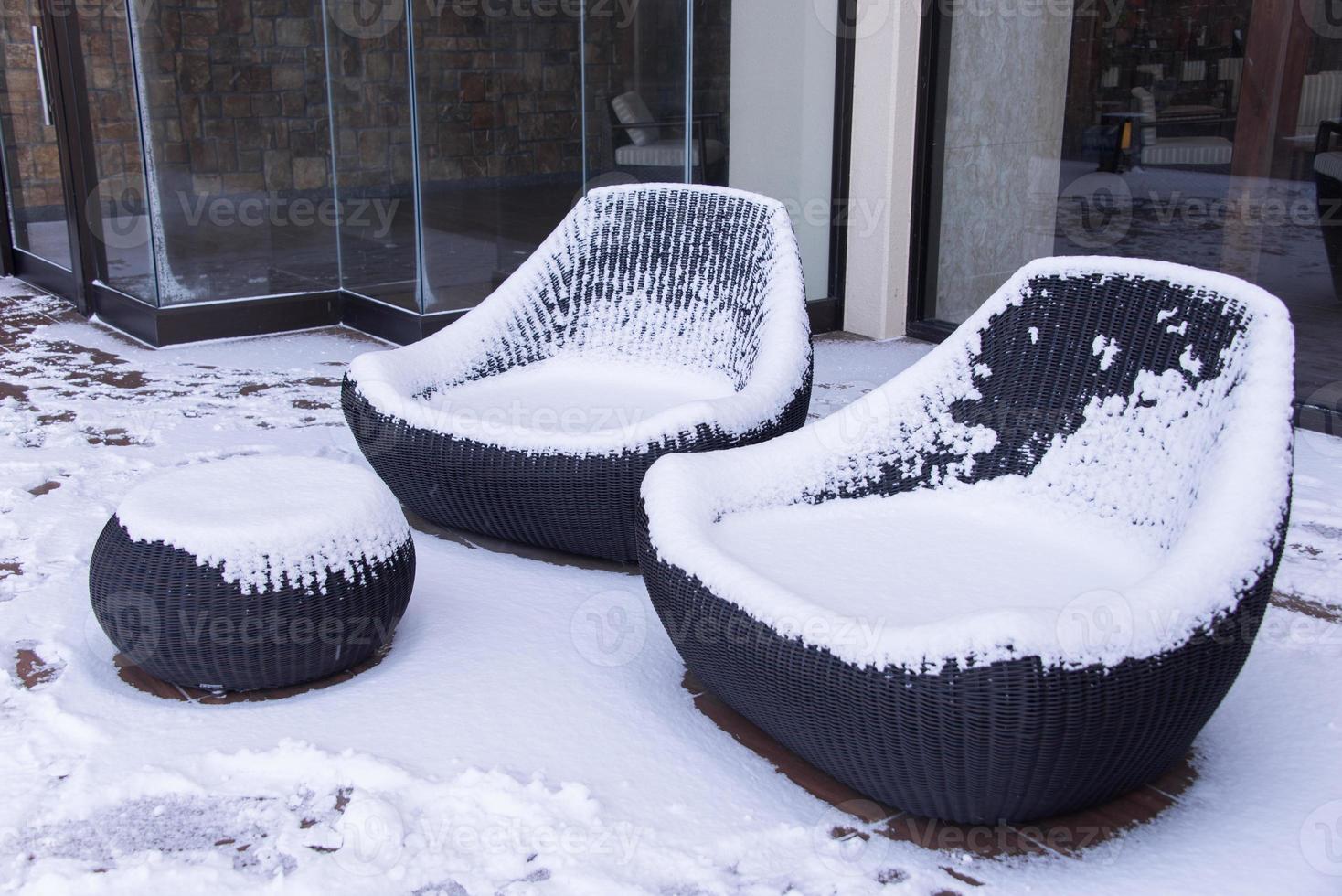 snö täckt stolar i trädgård foto