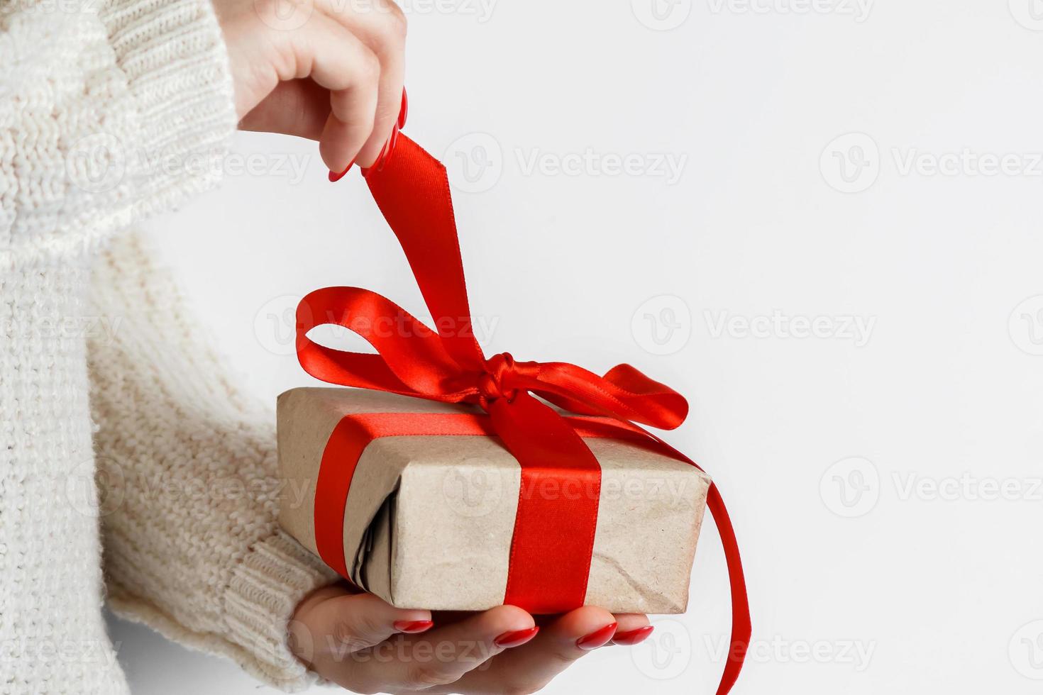 gåva med ett rött band i händerna på en vit bakgrund foto