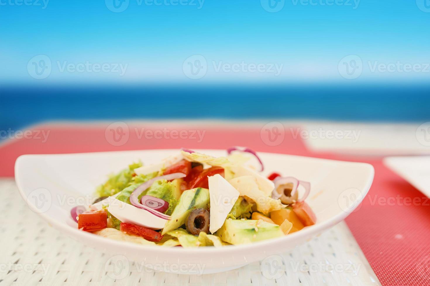 vegetarisk sallad i keramisk tallrik på det vita raffiabordet foto