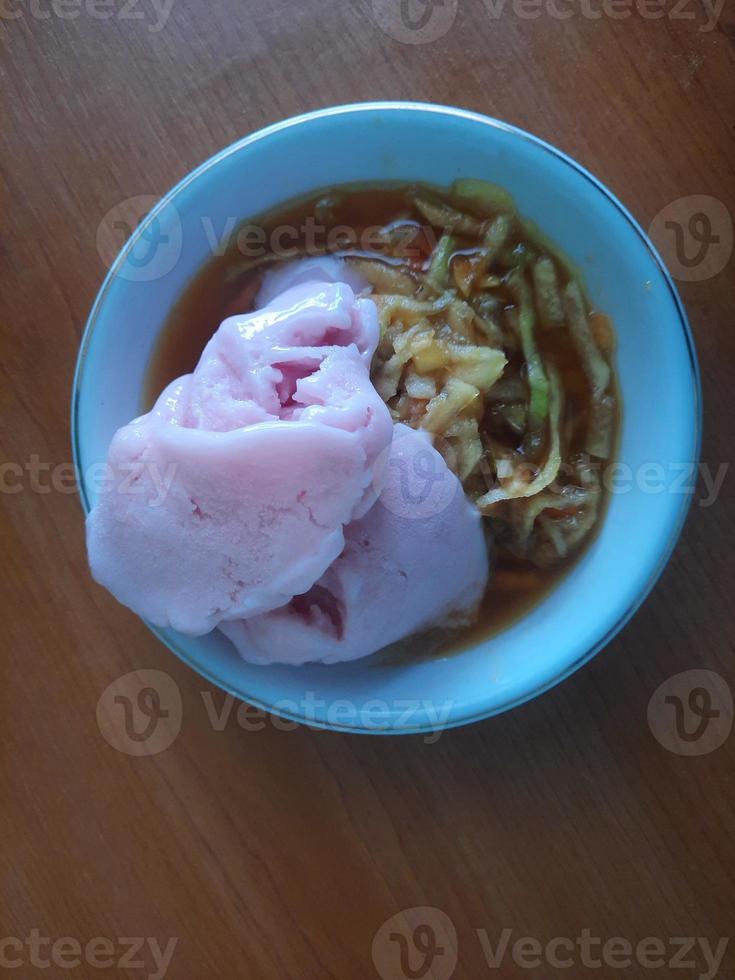 en Rujak eller kryddad frukt sallad maträtt toppade med jordgubb is grädde foto