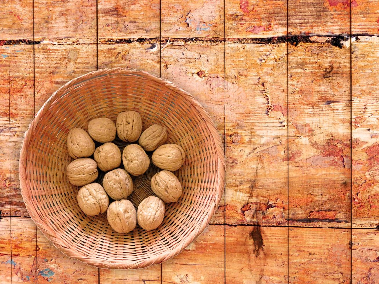 hela valnötter i en flätad skål på en träbordbakgrund foto