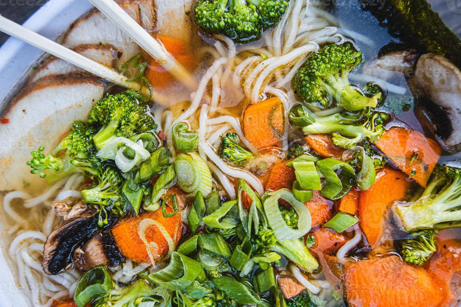skål av Ramen med ätpinnar och broccoli på topp foto