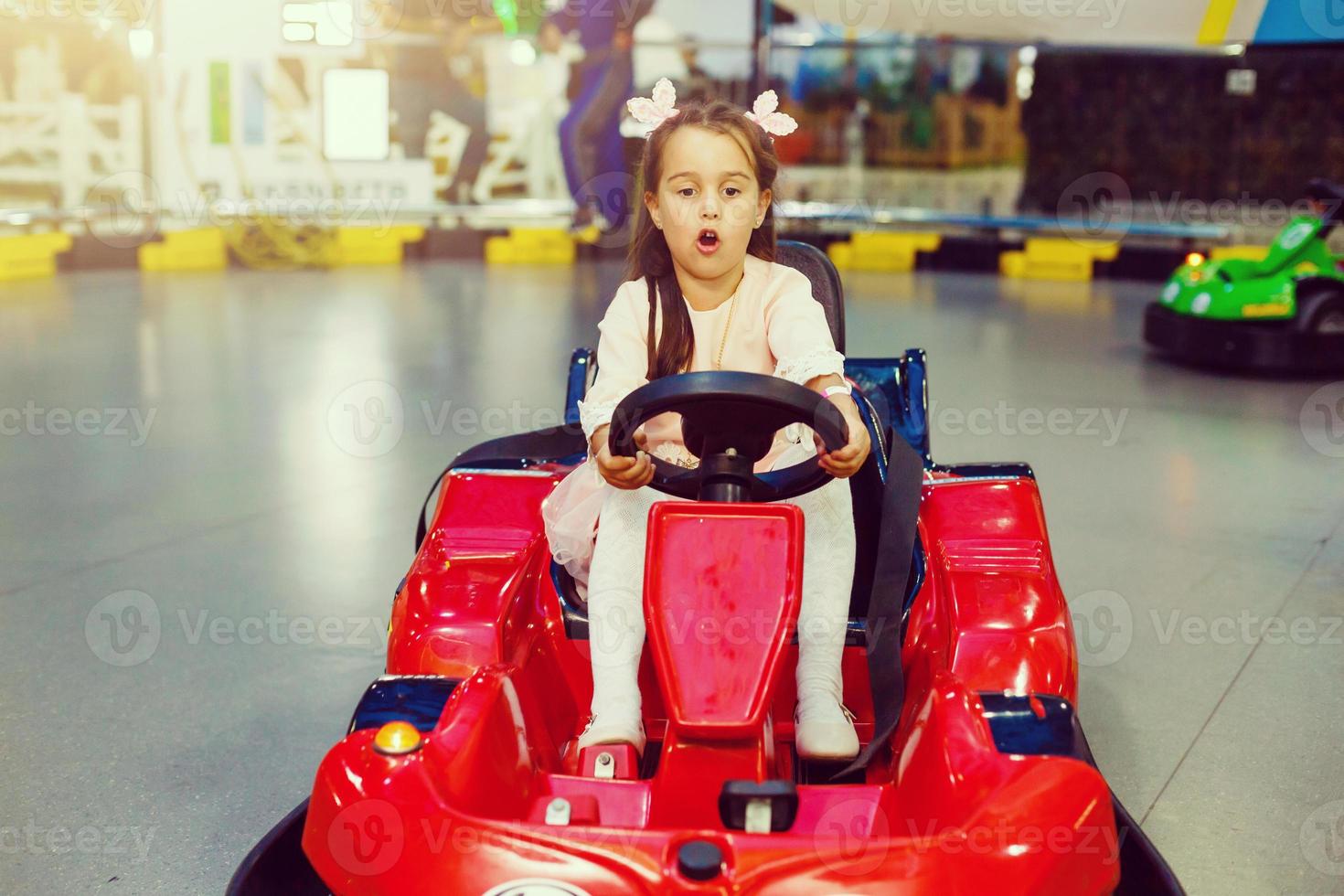 liten flicka körning leksak röd bil foto