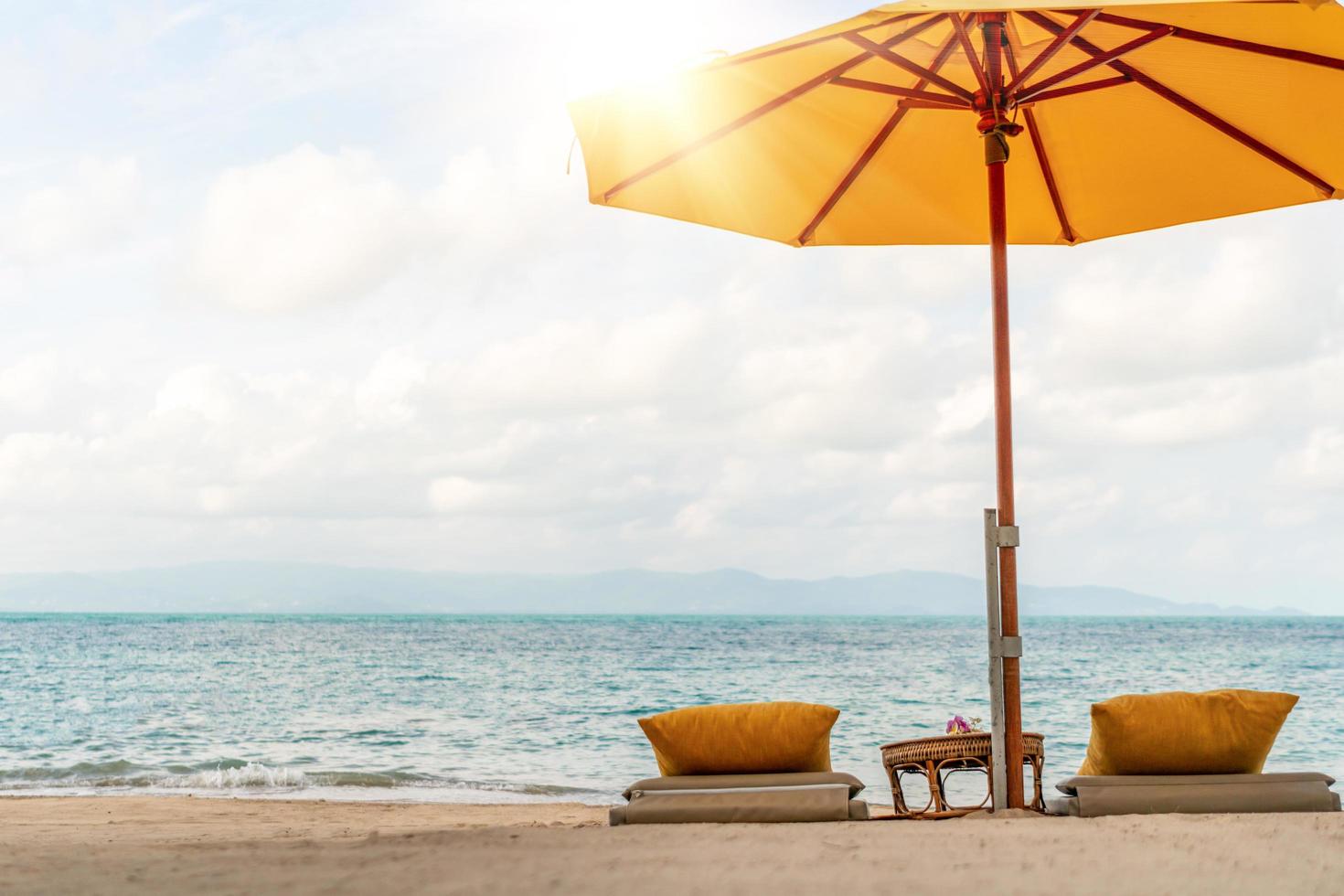 paraply och stol på en tropisk sommarstrandbakgrund med blå himmel för kopieringsutrymme foto