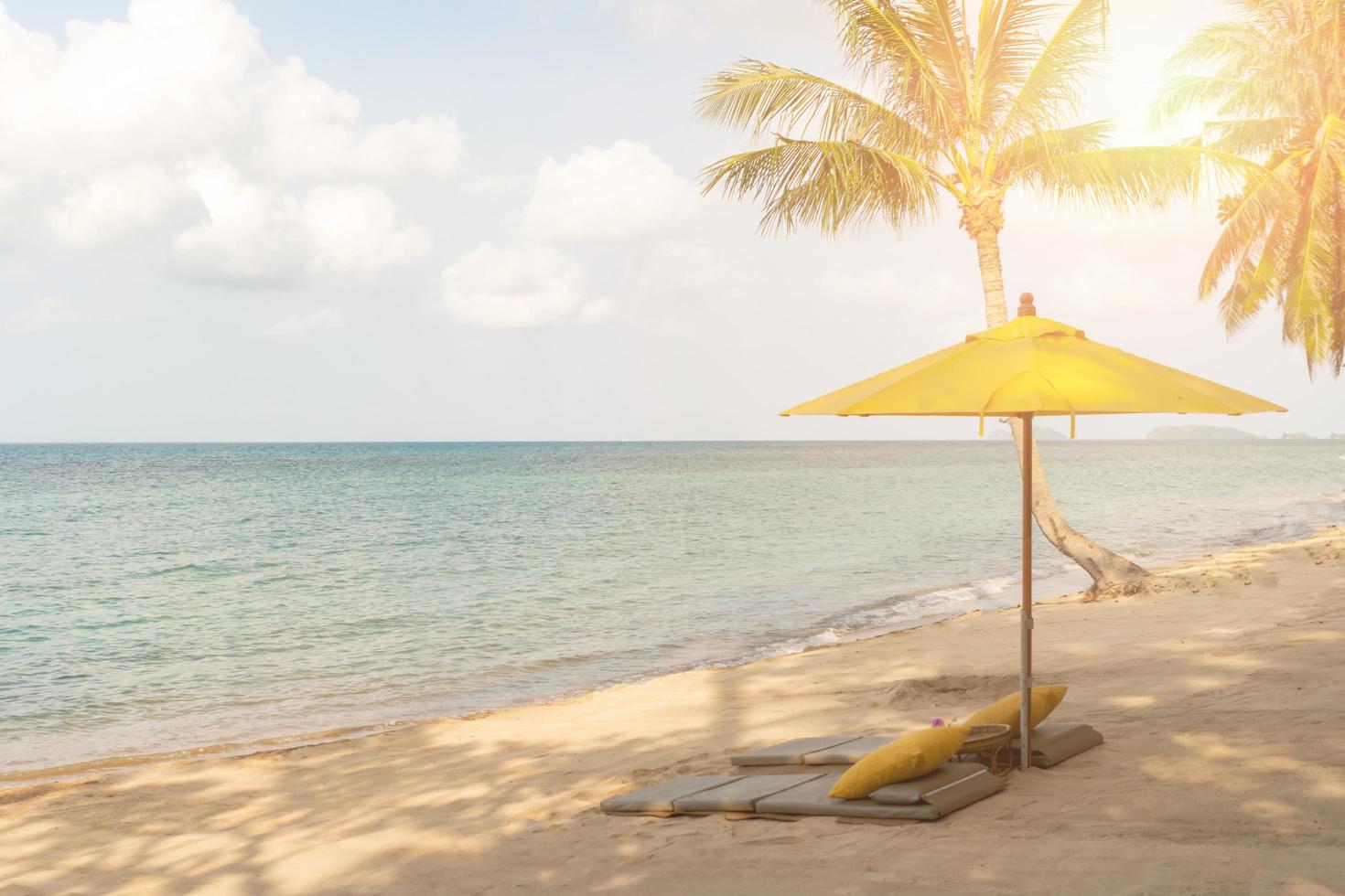 paraply och stol på en tropisk sommarstrandbakgrund med blå himmel för kopieringsutrymme foto