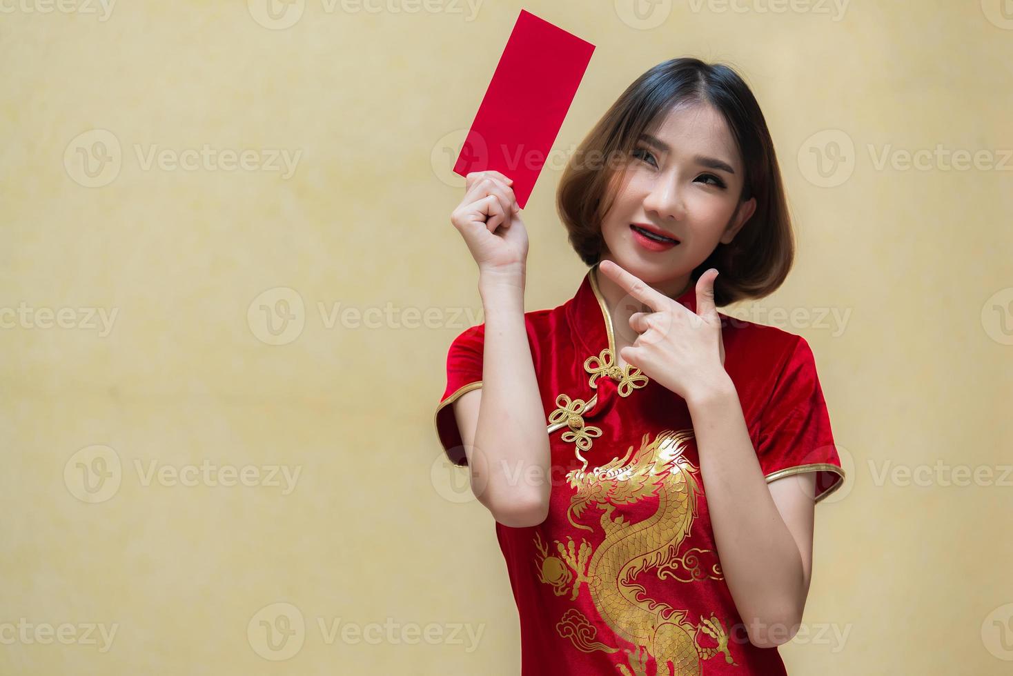 porträtt skön asiatisk kvinna i Cheongsam klänning, thailand människor, glada kinesisk ny år koncept, glad asiatisk lady i kinesisk traditionell klänning innehav en röd kuvert foto