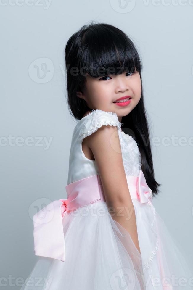 porträtt asiatisk söt liten flicka utgör för ta en Foto i studio på vit bakgrund