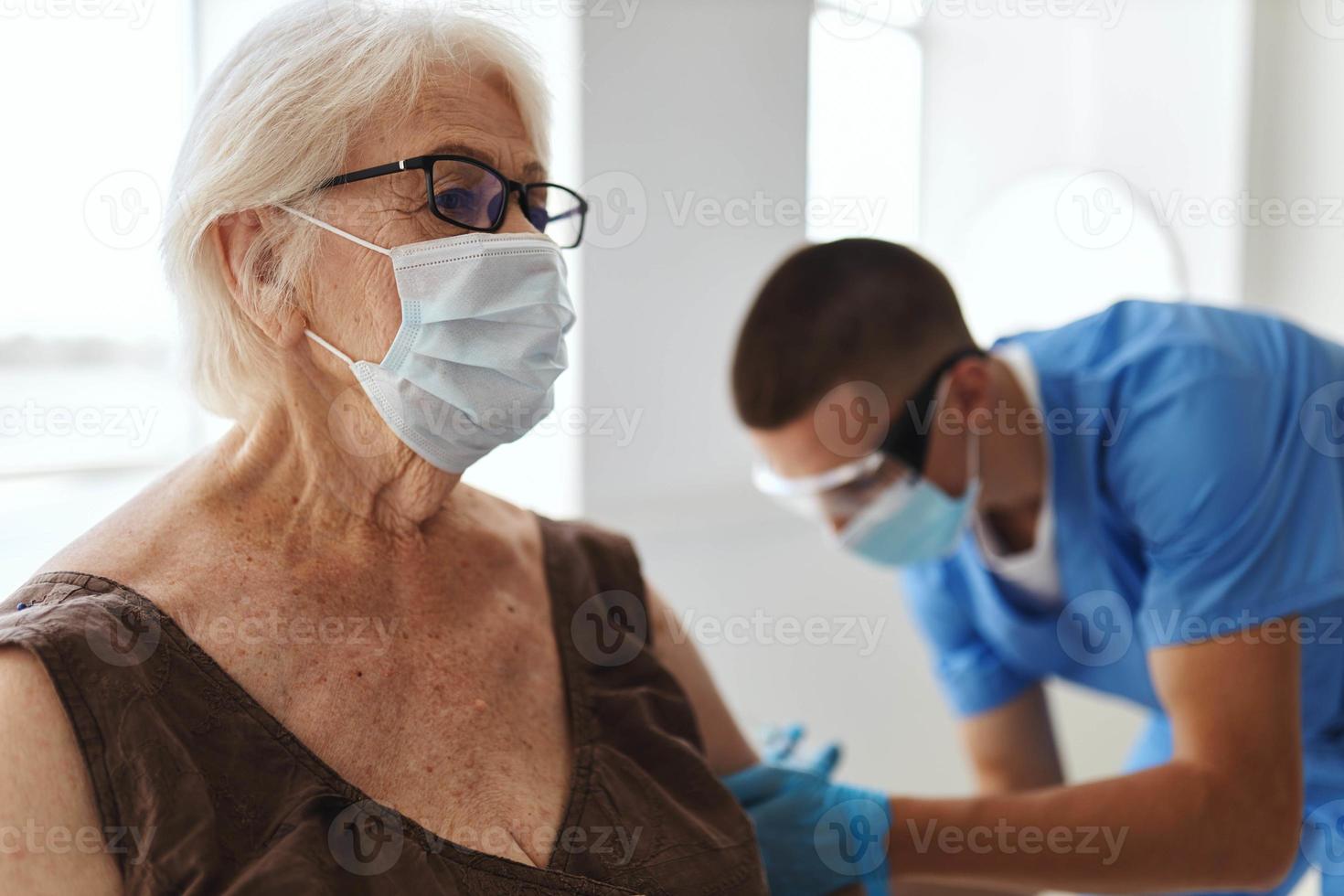 läkare ger ett injektion till ett äldre kvinna patient covid pass foto