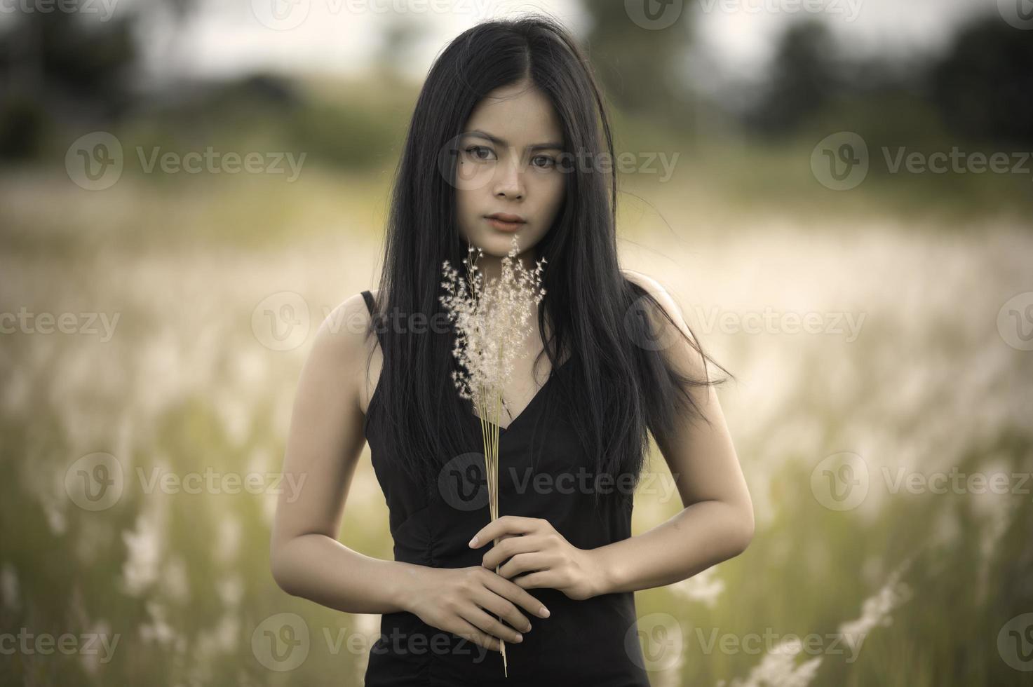 porträtt av skön asiatisk kvinna på gräs fält på solnedgång foto