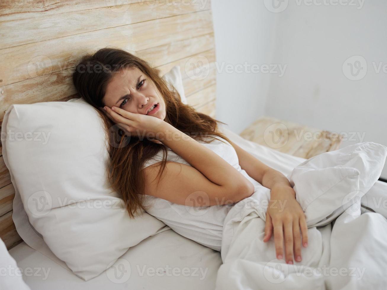 olycklig kvinna liggande i säng känsla sjuk hälsa problem foto