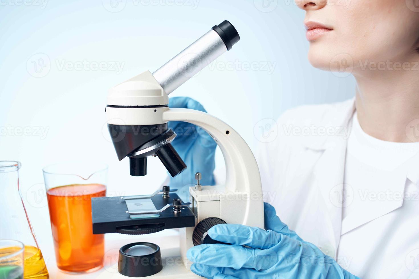kvinna laboratorium assistent i en medicinsk klänning mikroskop kemisk lösningar forskning foto