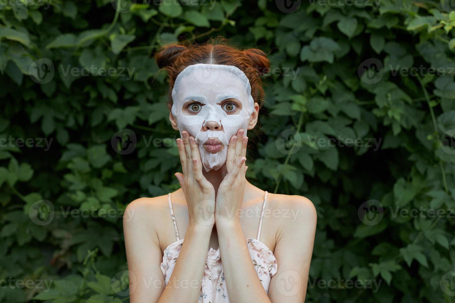 porträtt av en flicka anti rynkor mask överraskad till Rör din ansikte med din händer hud vård buskar i de bakgrund foto