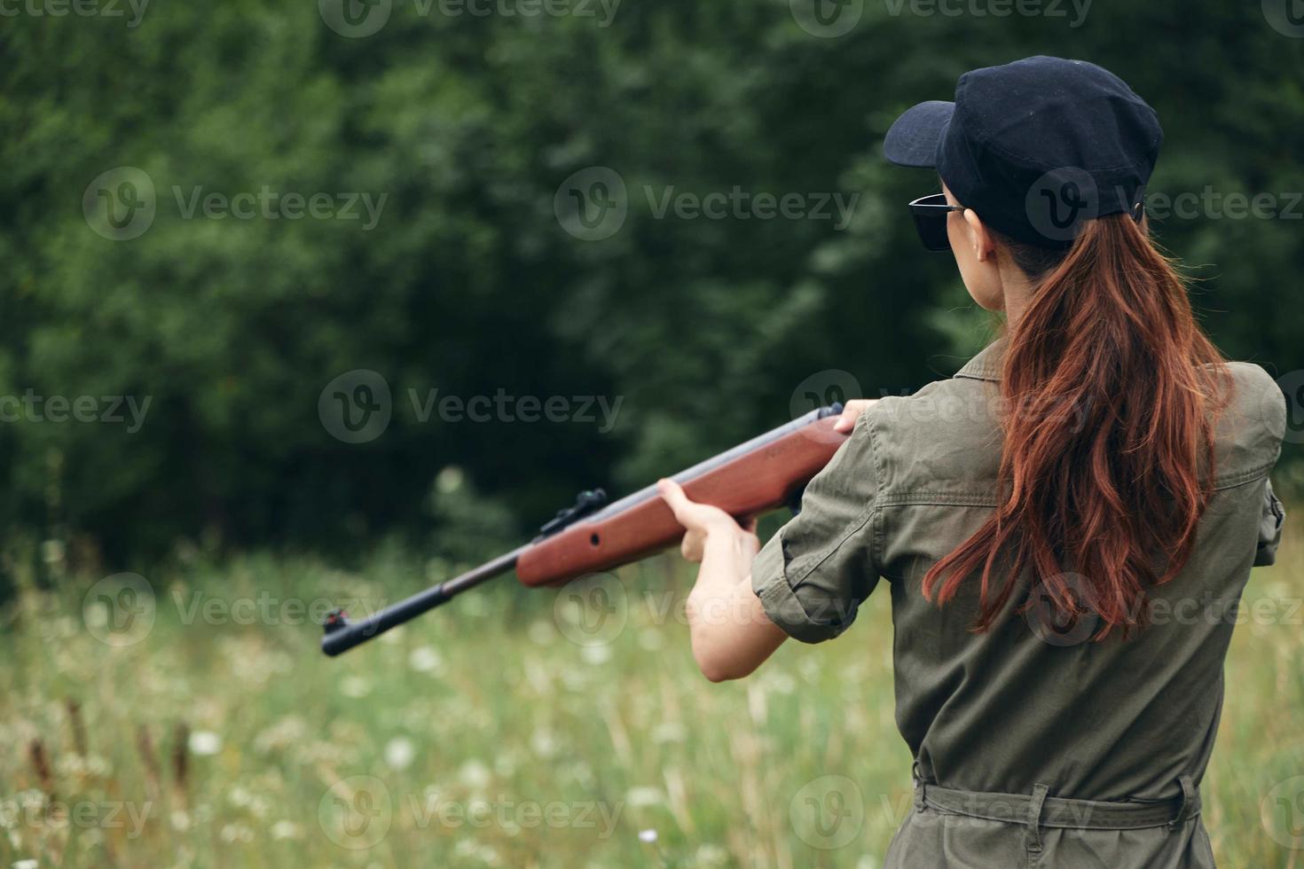 kvinna på utomhus- innehav en vapen är en jakt livsstil svart keps foto