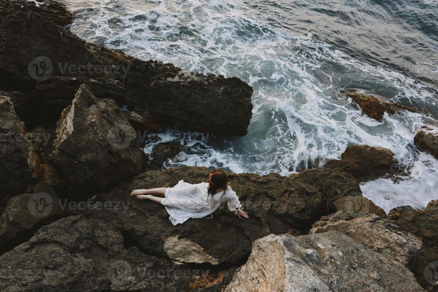 skön brud liggande på klippig kust med sprickor på klippig yta oförändrad foto