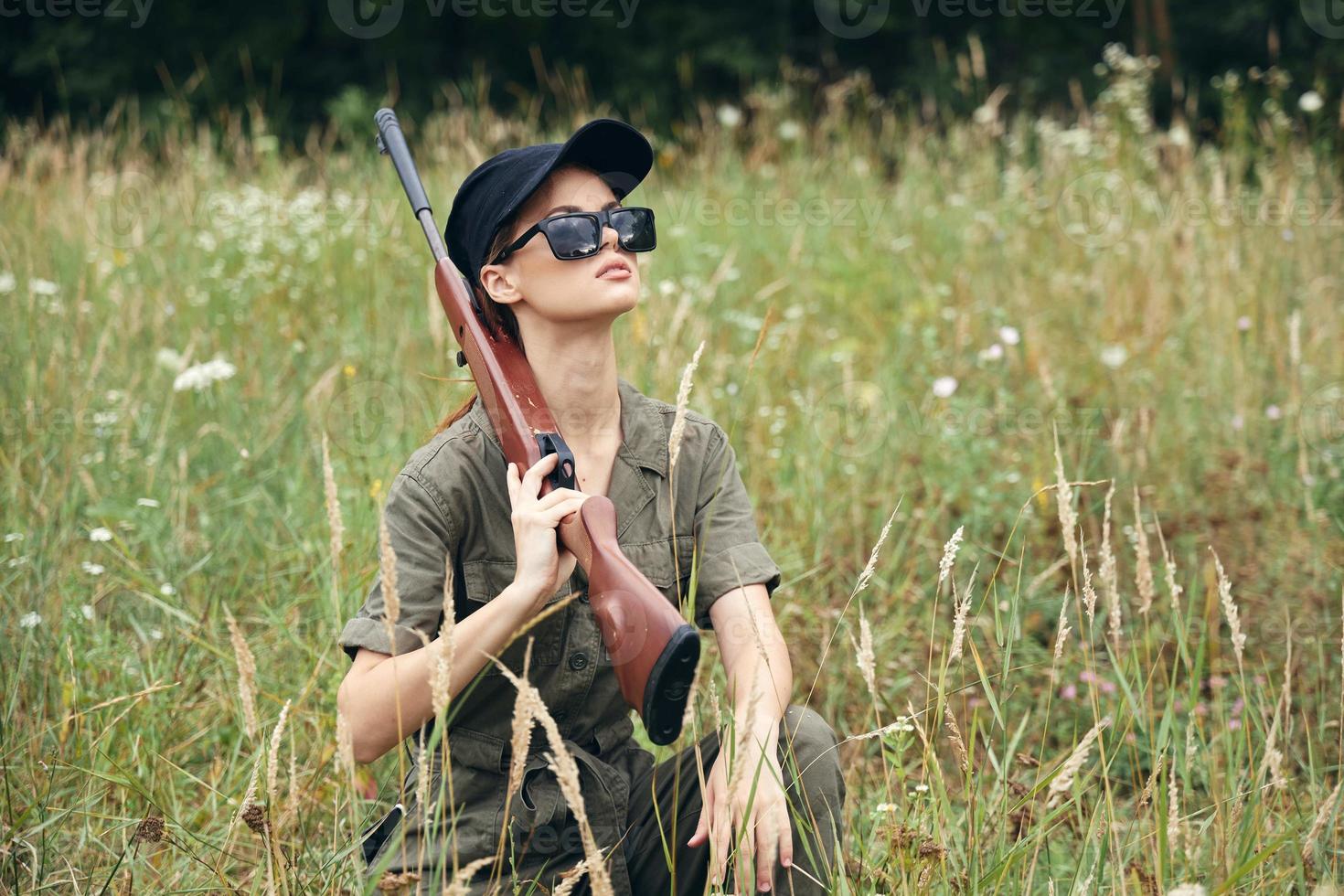 militär kvinna solglasögon med vapen hukande grön löv foto