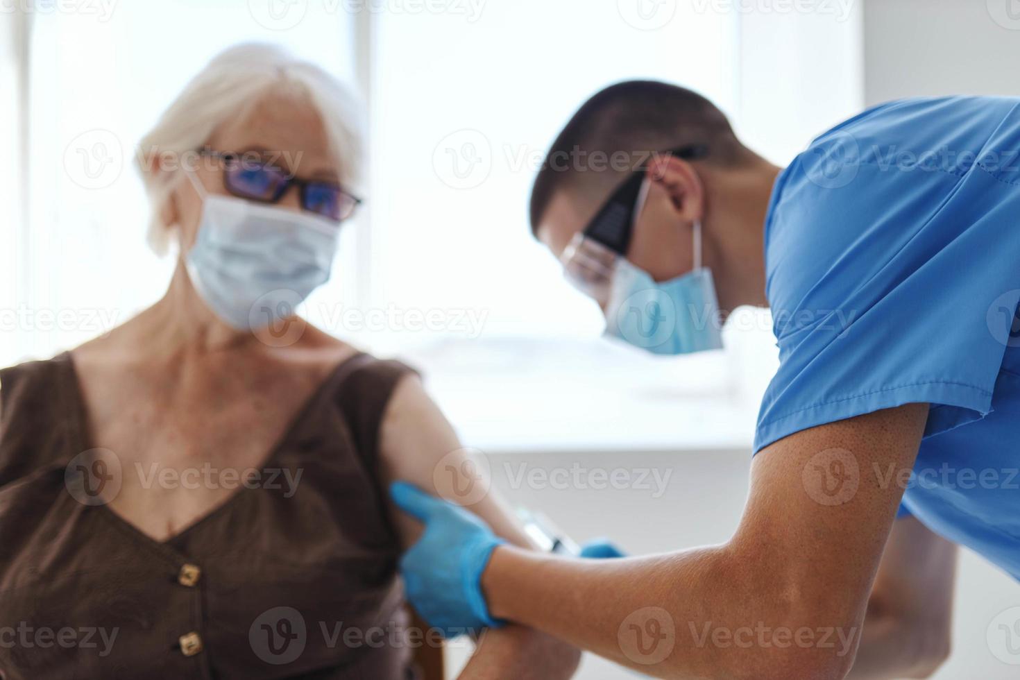 manlig läkare ger ett injektion till ett äldre kvinna patient covid pass foto