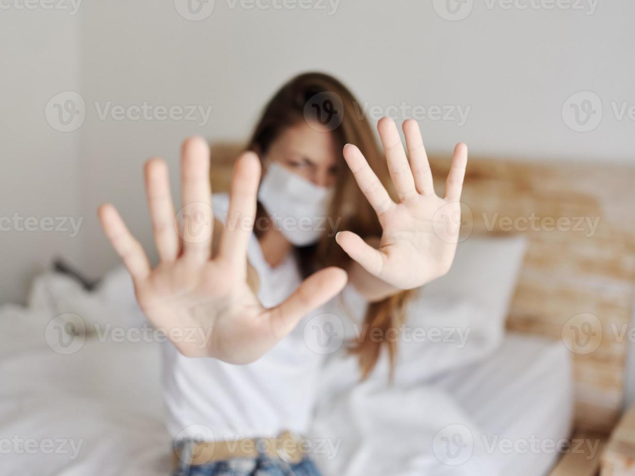 kvinna täckt med händer från kamera medicinsk mask isolerat rum säng kuddar karantän foto