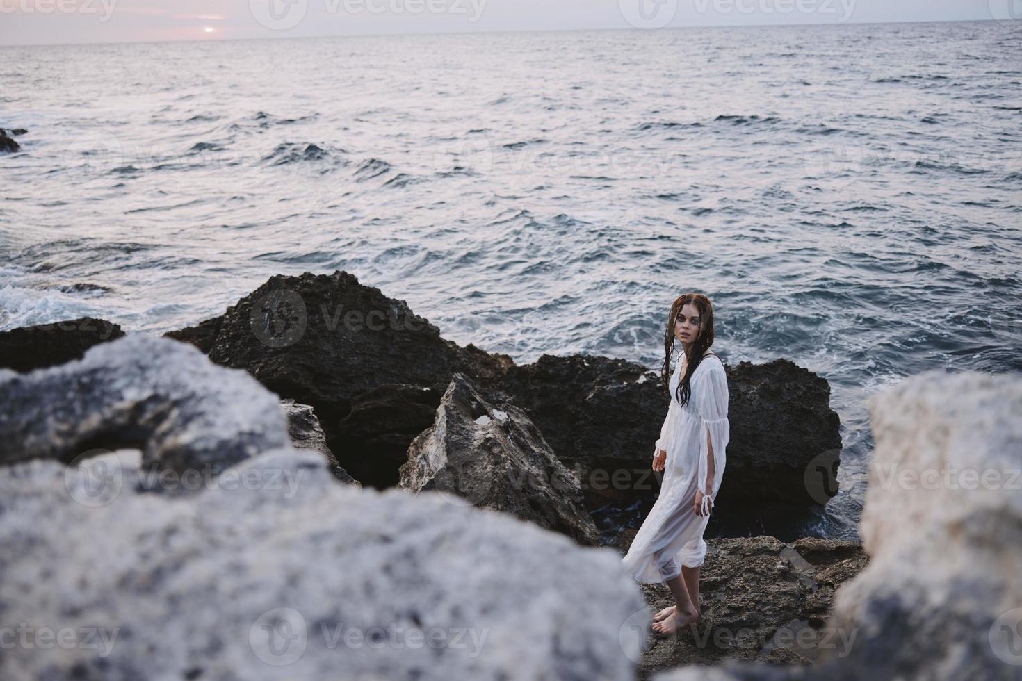 kvinna står på stenar i vit klänning hav natur resa foto