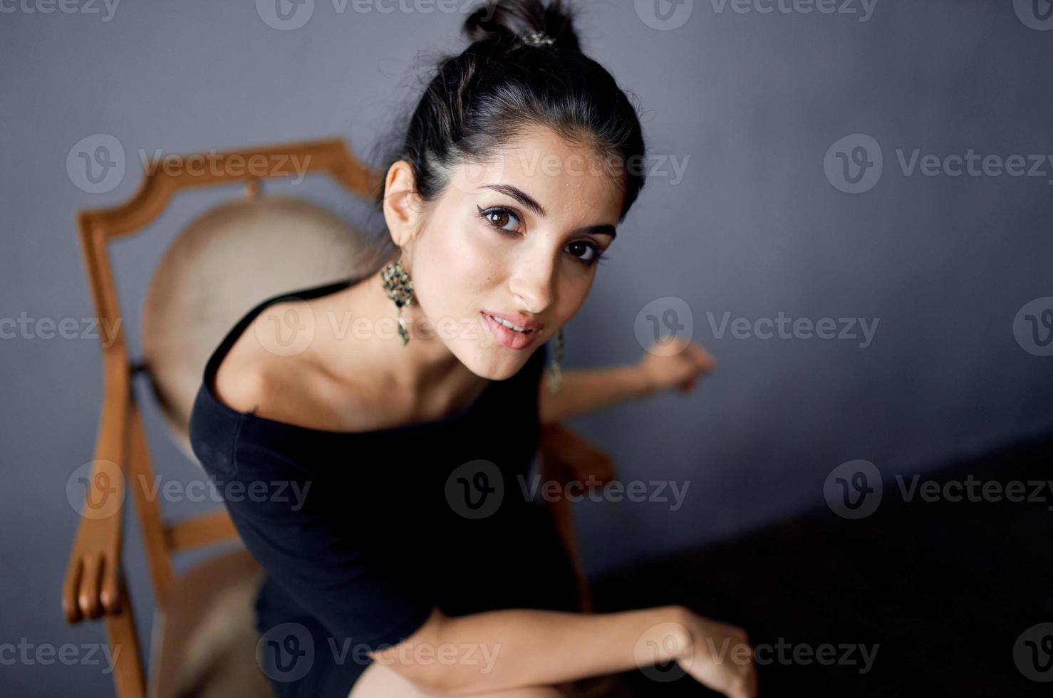 Söt kvinna örhängen Smycken Framställ nära de stol svart klänning isolerat bakgrund foto