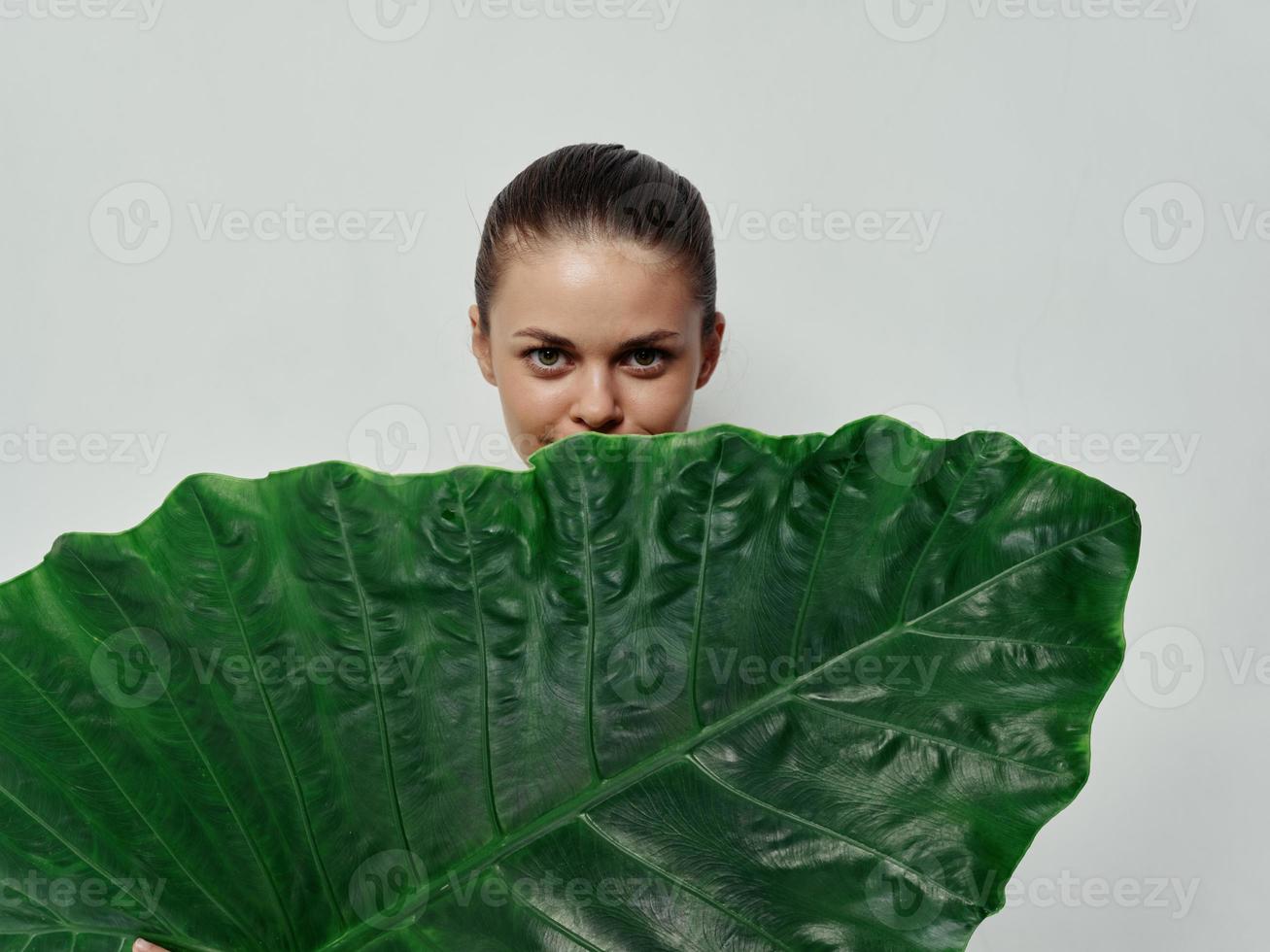 Söt kvinna kikar ut från Bakom en handflatan blad studio foto