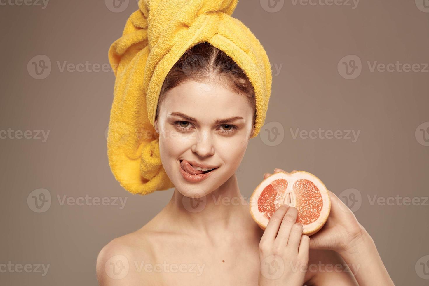 skön kvinna med en gul handduk på henne huvud exotisk frukt citrus- vitaminer hälsa foto