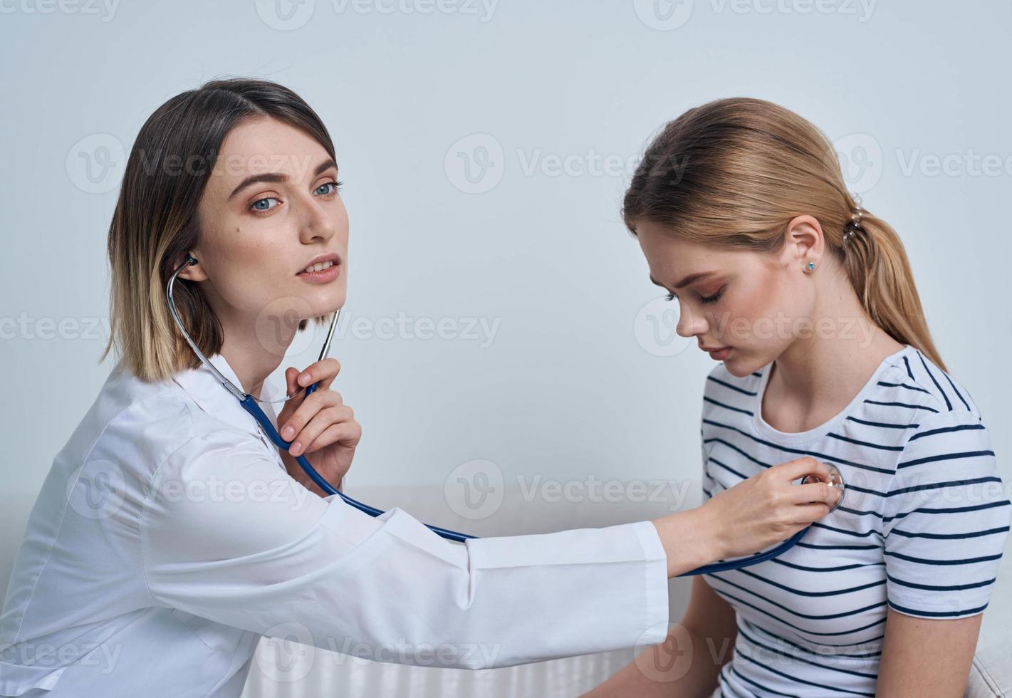 kvinna läkare med stetoskop och patient på de reception foto