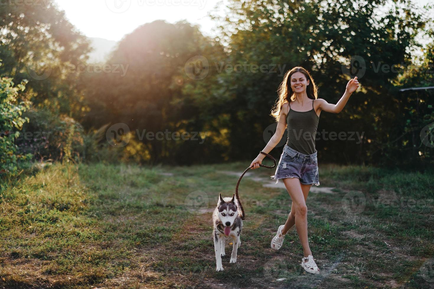 en kvinna kör med en hund i de skog under ett kväll promenad i de skog på solnedgång i höst. livsstil sporter Träning med din älskad hund foto