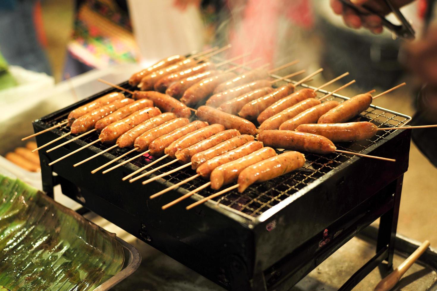 närbildrad av grillkorv på kolgrillen med rök foto