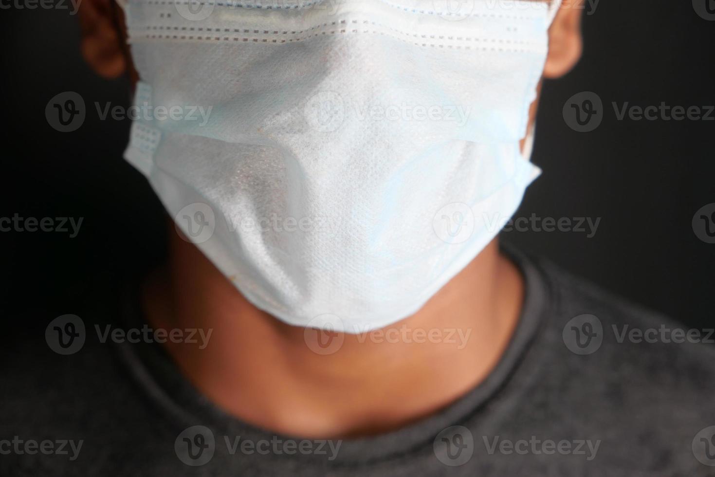 närbild på mannen med skyddande ansiktsmask isolerad på svart foto