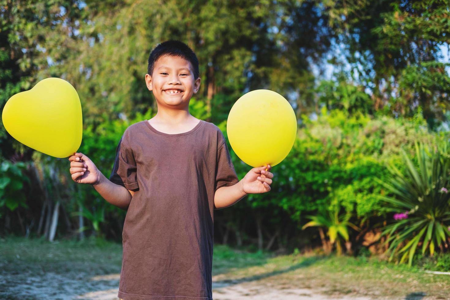 glad pojke som håller gula ballonger foto