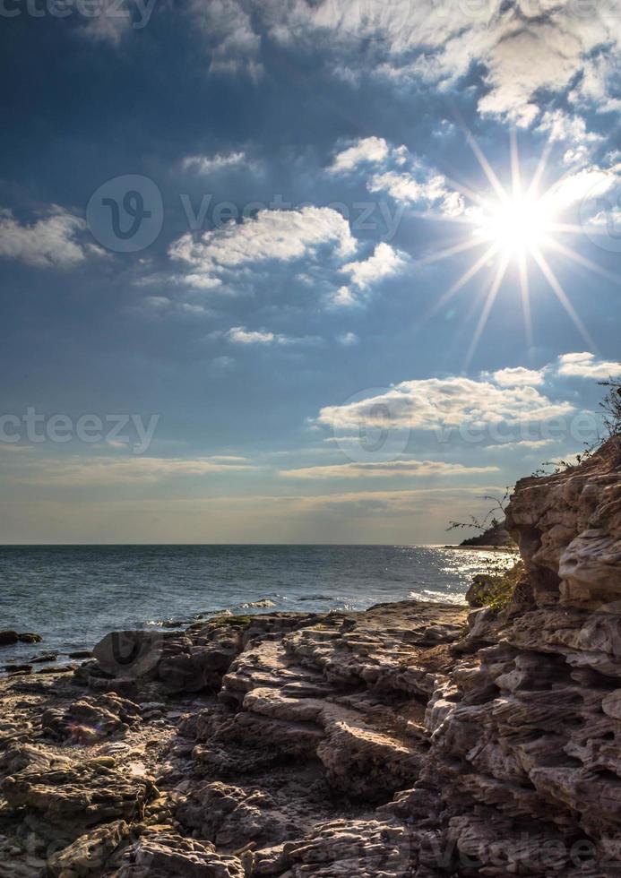 solen ovanför en stenig strand foto