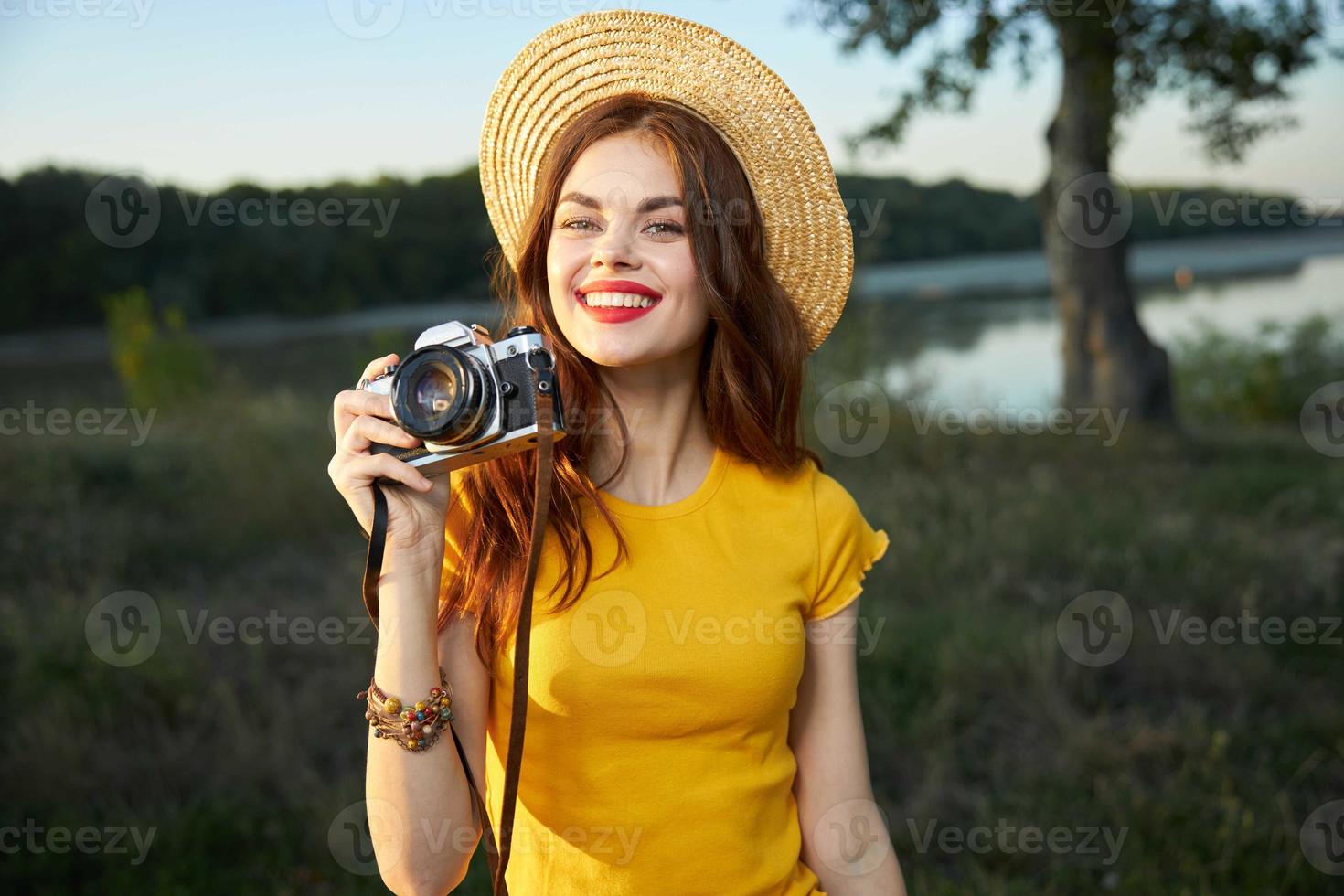 vanlig kvinna fotograf med en kamera i henne händer bär en hatt röd mun natur foto
