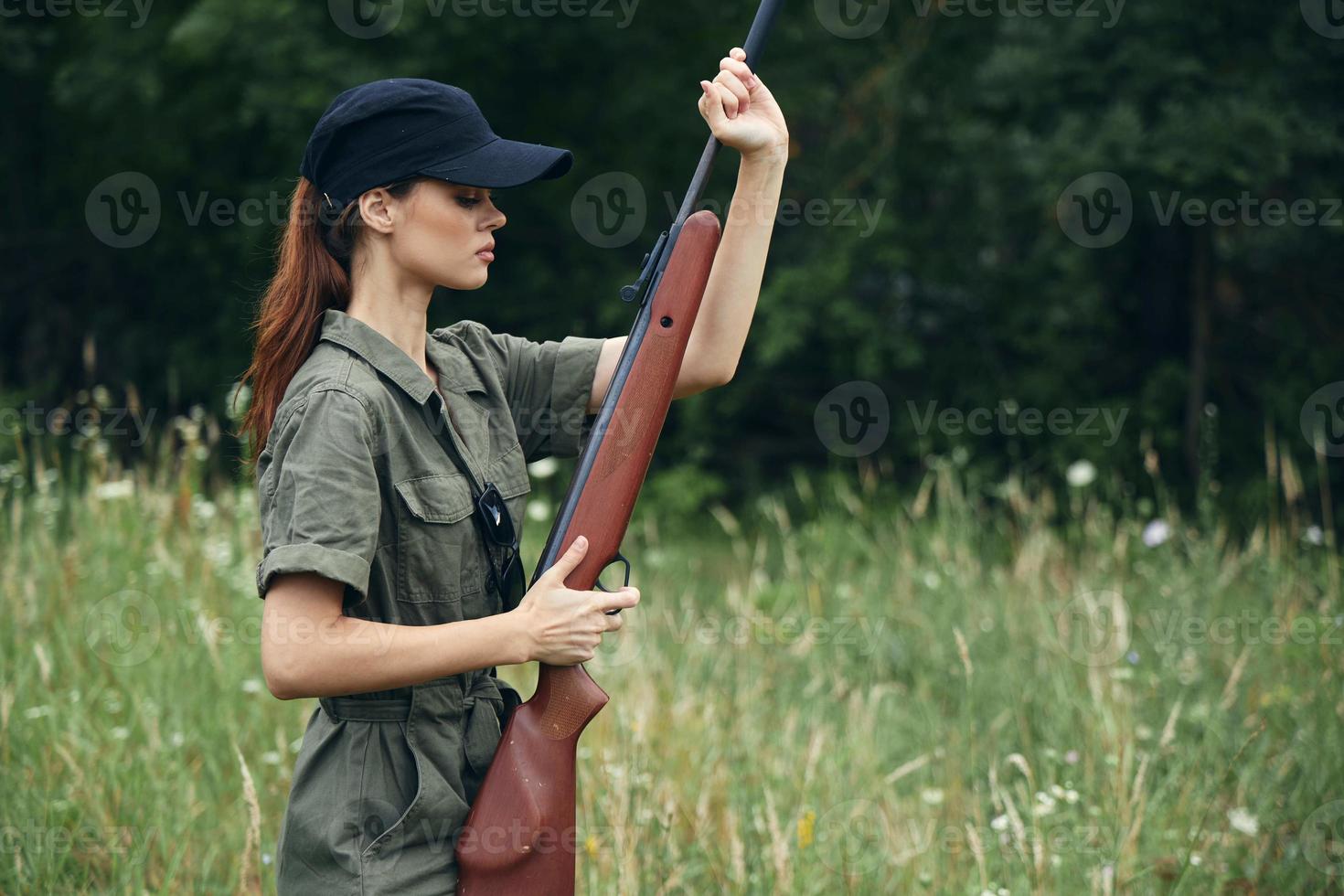 kvinna svart keps och en grön overall är innehav en vapen i hans händer foto