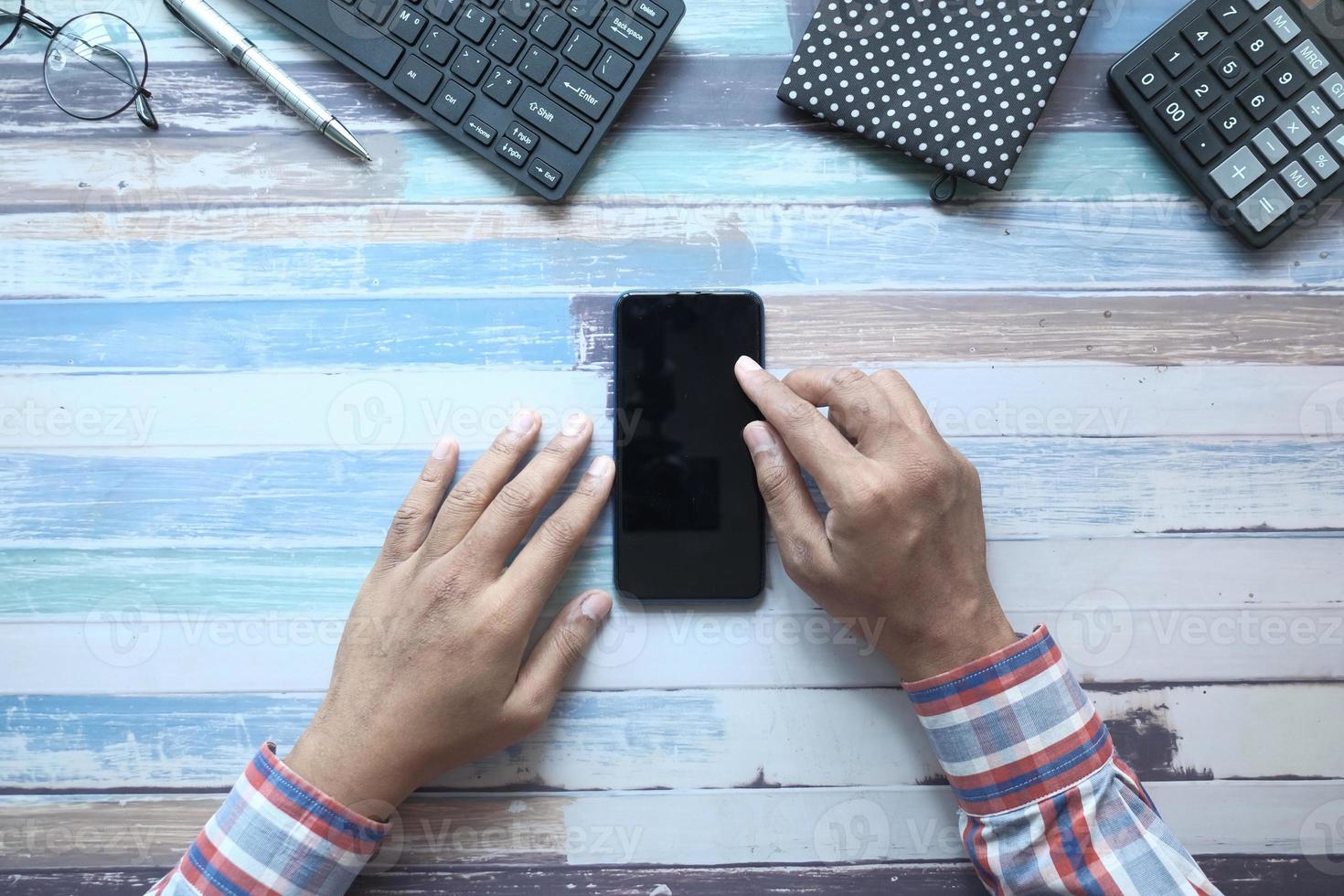 platt sammansättning av handen med smart telefon på trä bakgrund foto