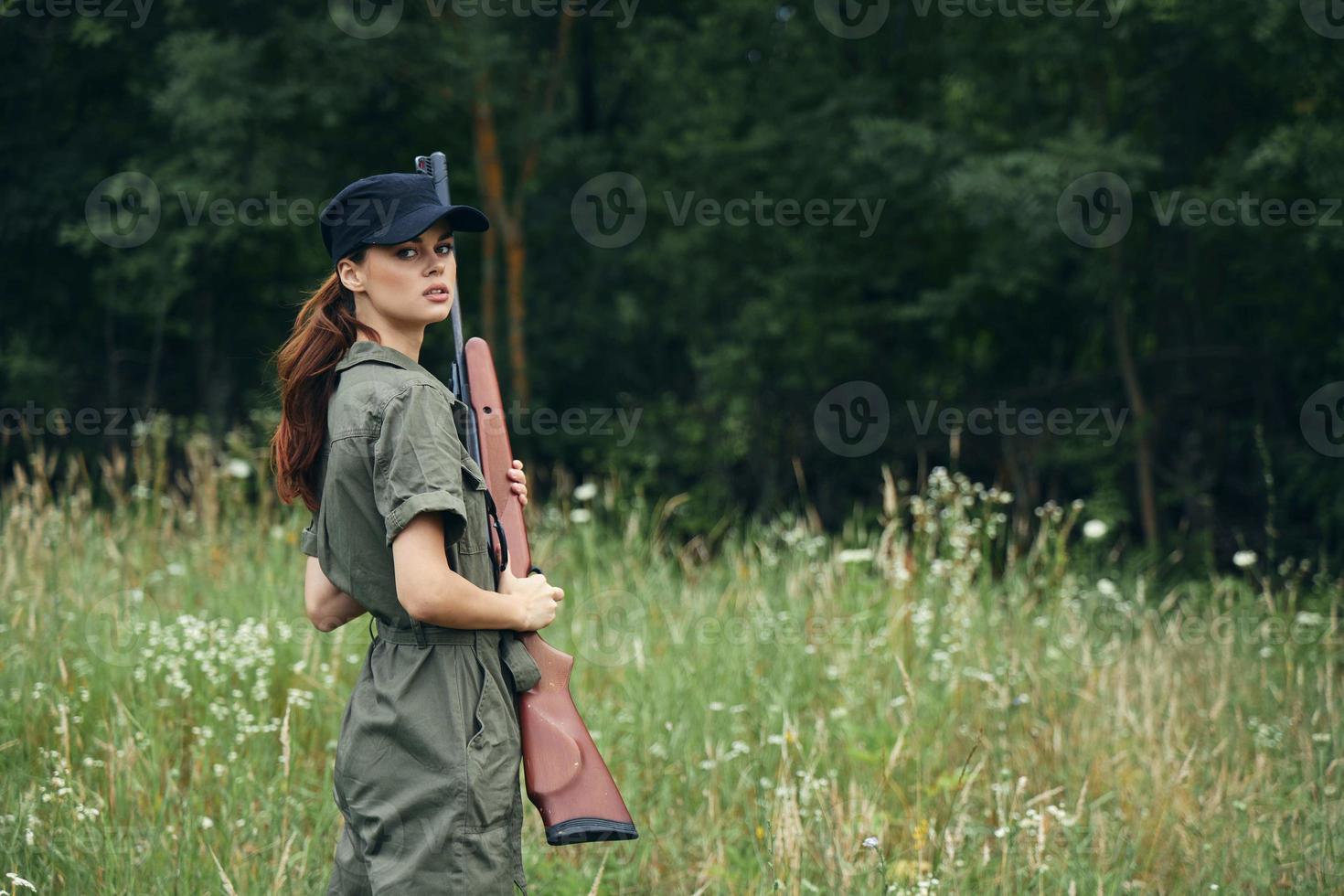 kvinna innehav en pistol i hans händer svart keps resa livsstil grön overall foto