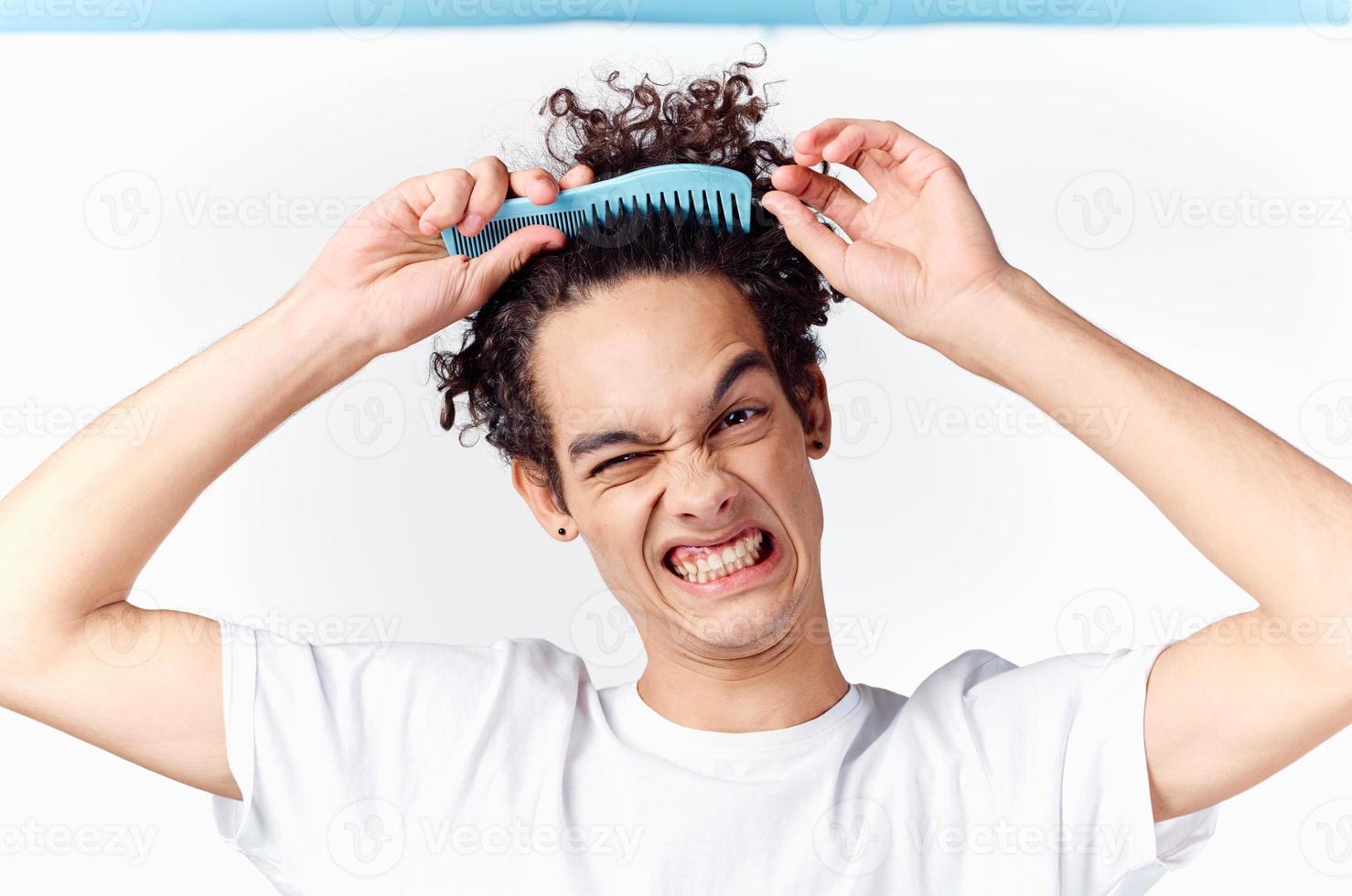 lockigt kille fastnat hårkam i hans hår känslor ljus bakgrund foto
