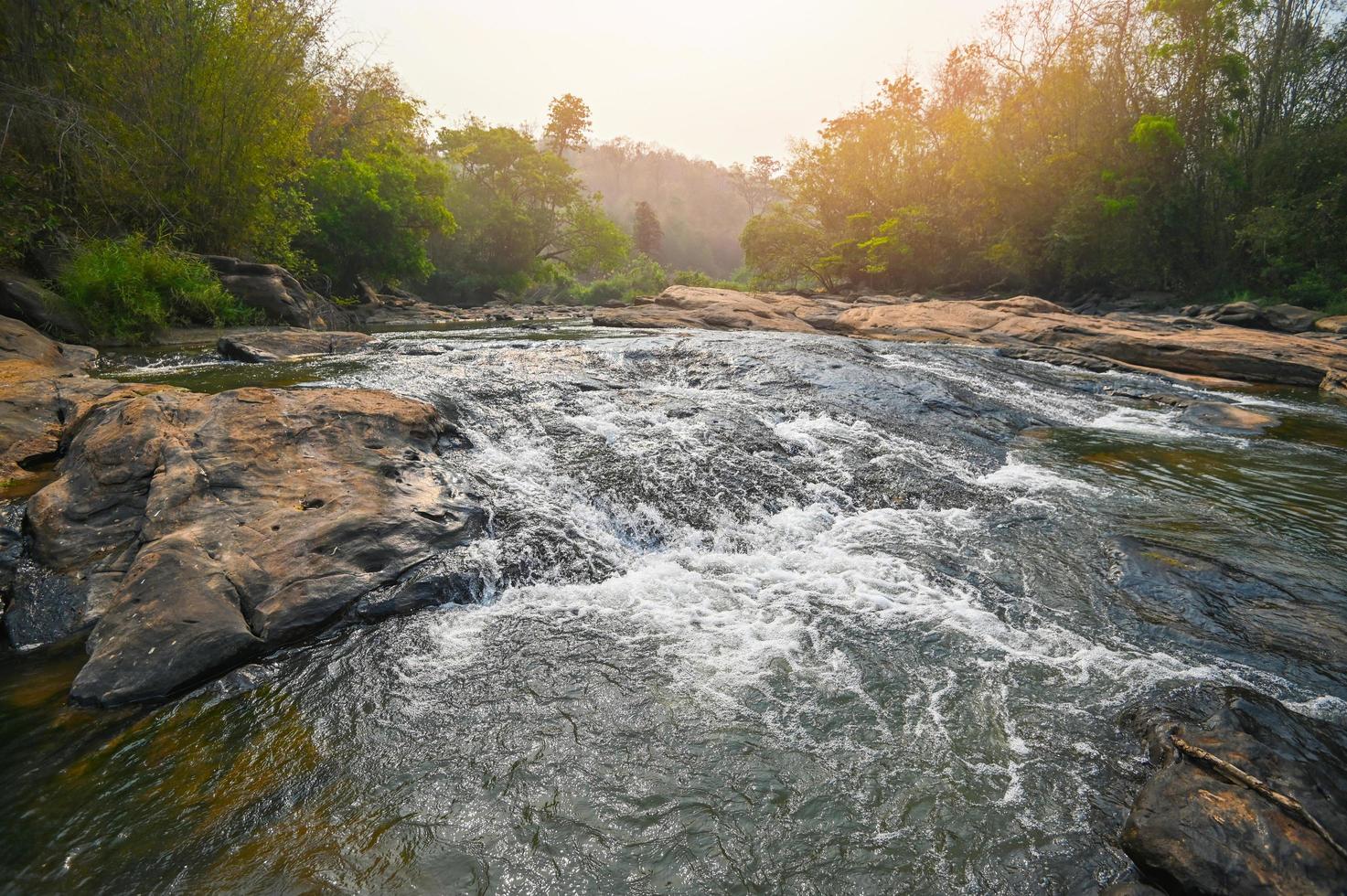 flod ström vattenfall i skog landskap, skön natur vatten ström med stenar i de tropisk skog liten berg vattenfall vatten strömmande och sten klar vatten i berg flod med träd foto