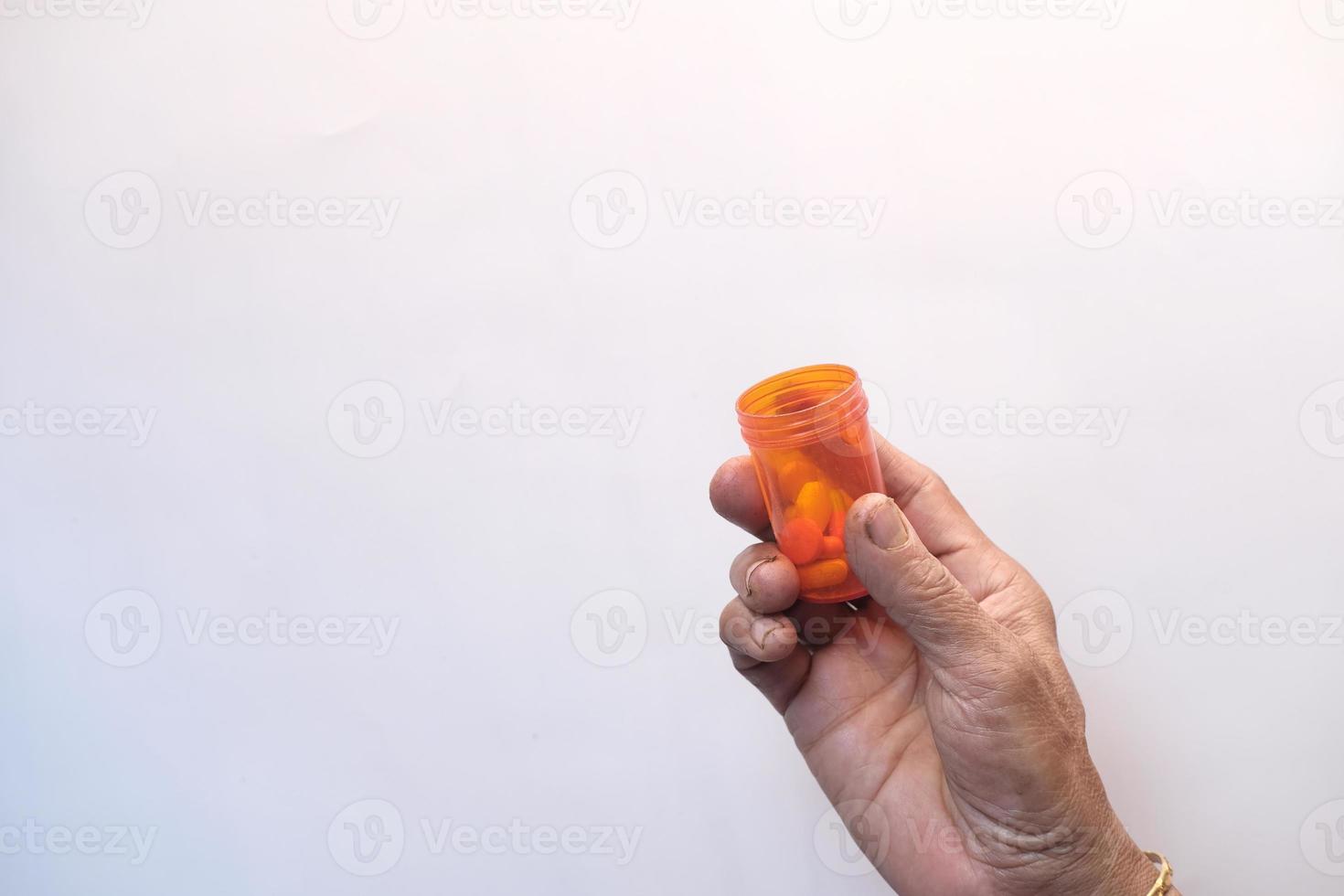 person som håller orange pillerbehållare foto