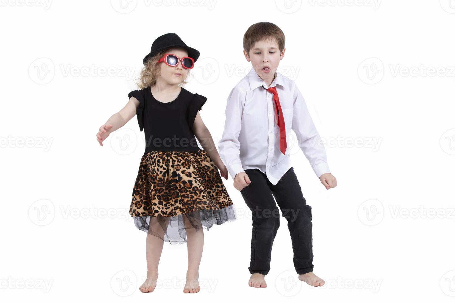 rolig barn dans på en vit bakgrund. liten flicka i en hatt och en pojke i en slips är dans. balsal dans. dansa par foto