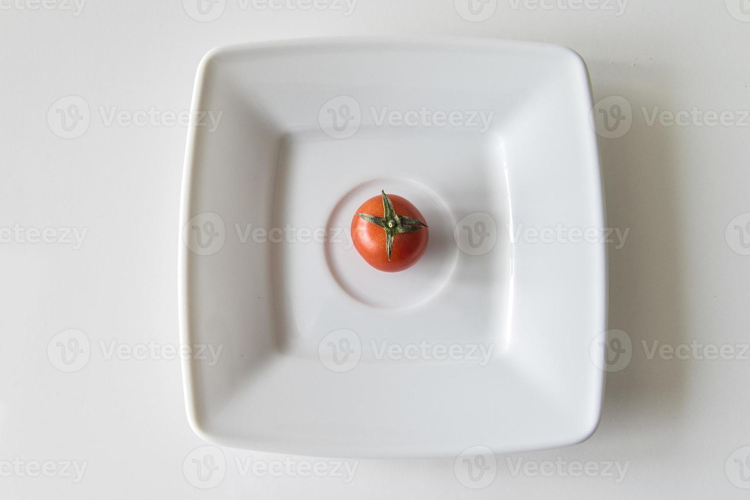 röd mogen saftig tomat på en vit tallrik i närbild foto