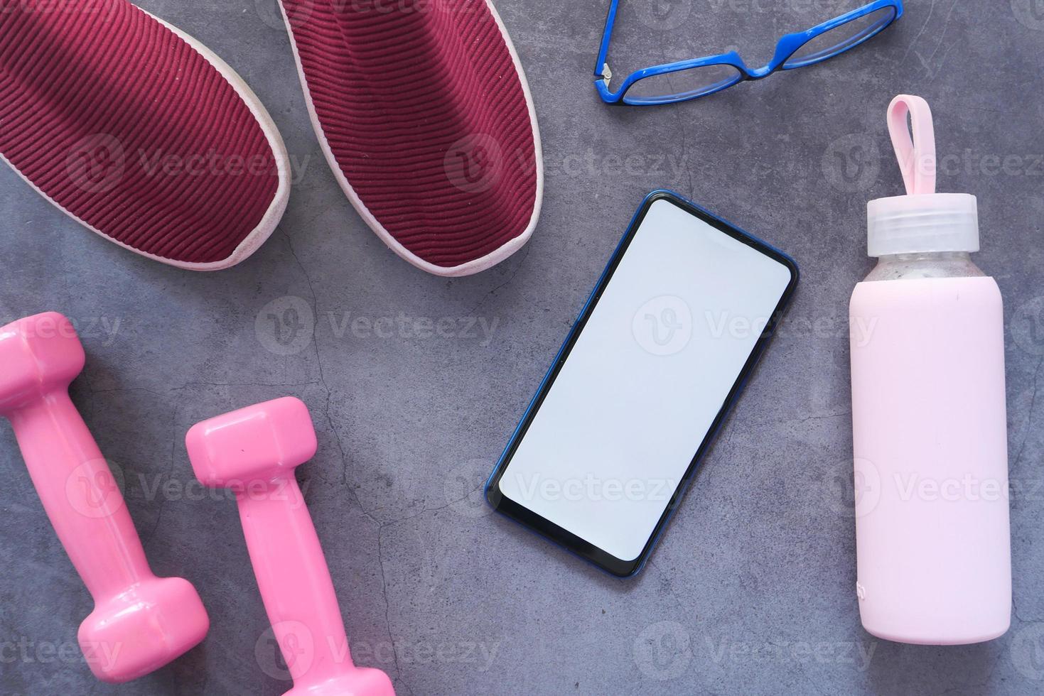 smart telefon med sportutrustning på grå bakgrund foto