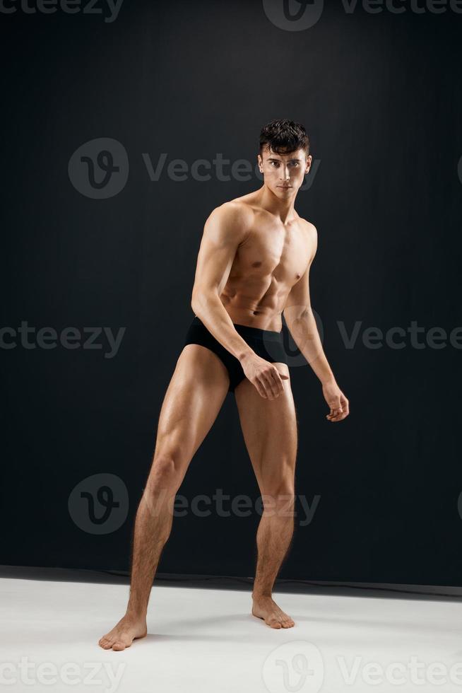 man i svart shorts med en muskulös kropp på en mörk bakgrund foto