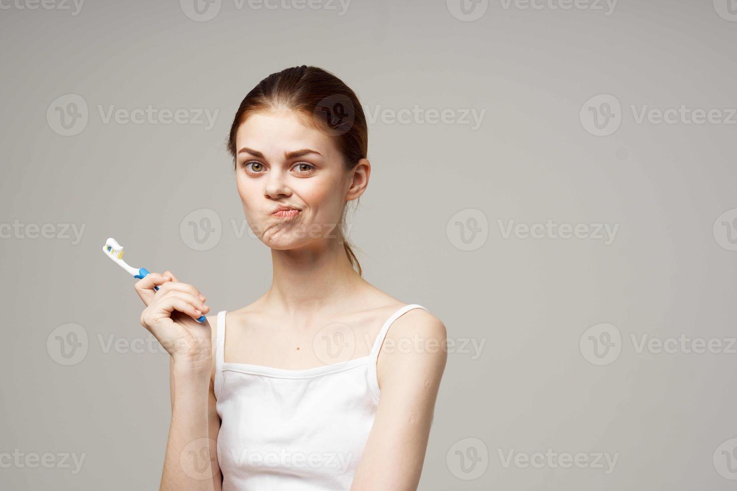 glad kvinna med en tandborste i hand morgon- hygien ljus bakgrund foto
