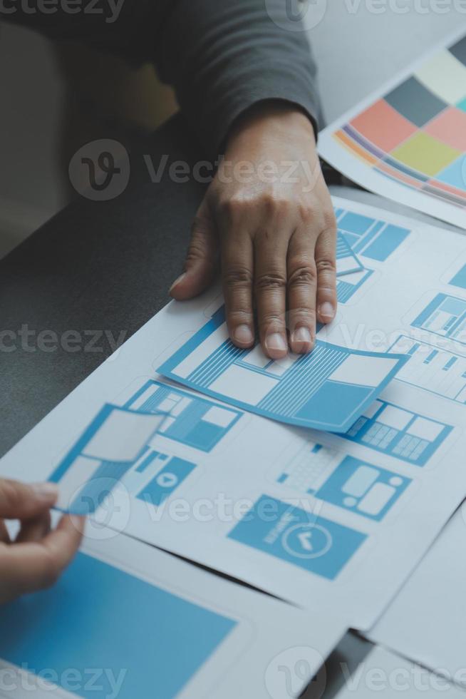 stänga upp ux utvecklare och ui designer brainstorming handla om mobil app gränssnitt trådmodell design på tabell med kund kortfattat och Färg koda på modern office.creative digital utveckling byrå foto